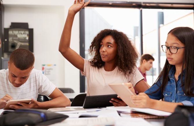 Teenage,Schoolgirl,Raising,Hand,In,Class